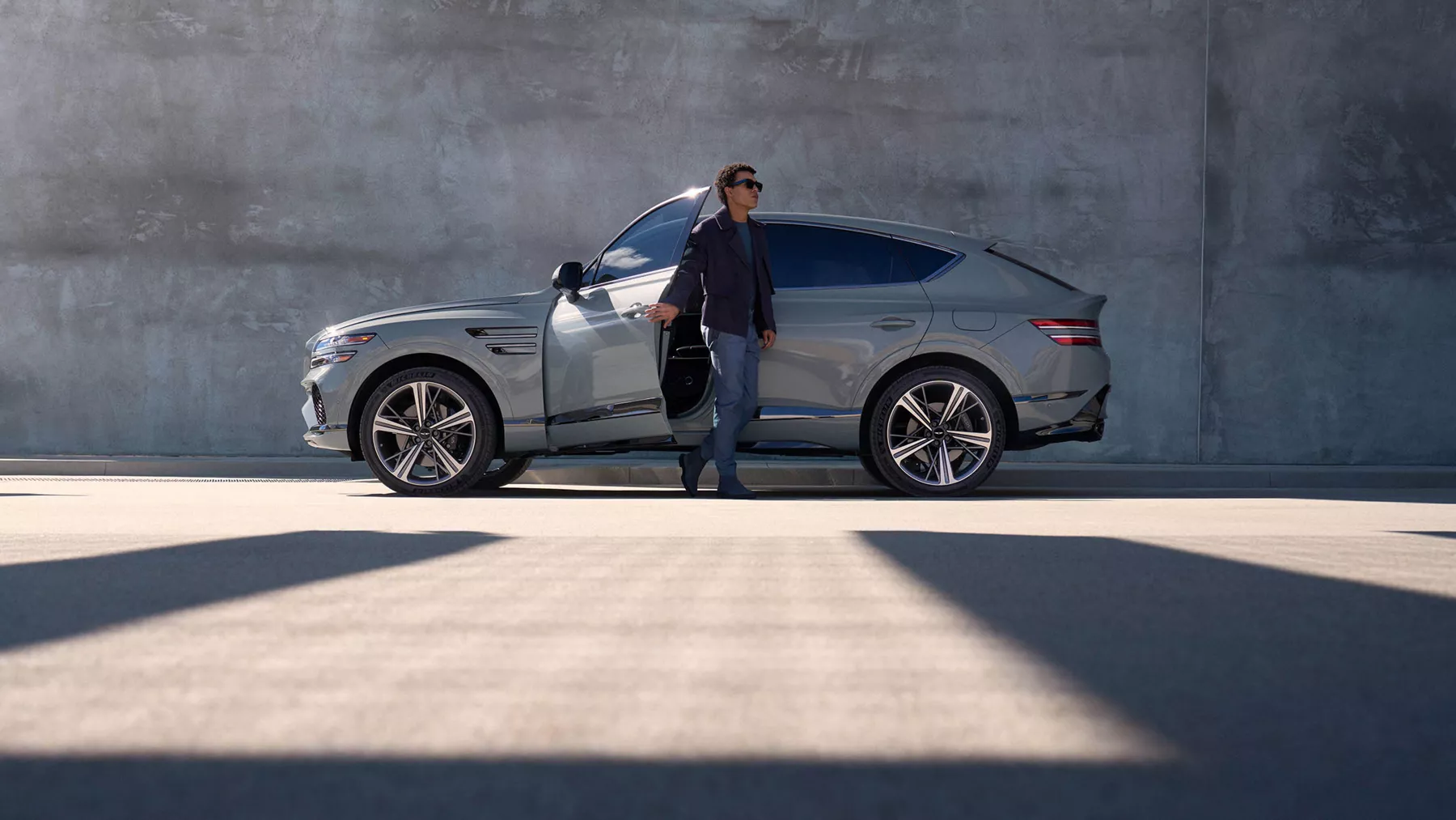 Side profile view of the GV80 Coupe with a person exiting the car.