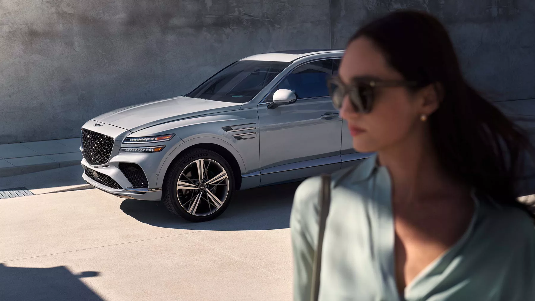 Side profile shot of the GV80 Coupe with a woman in the foreground. 