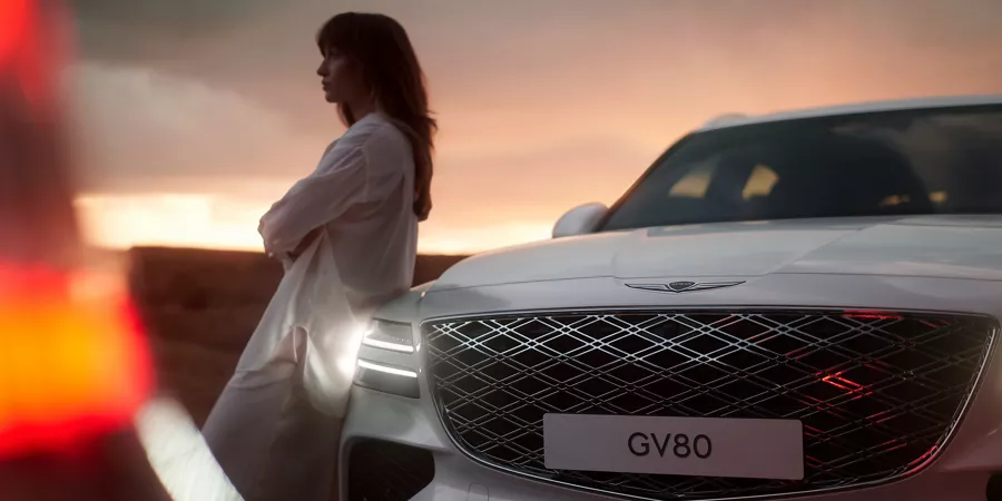 GV80 front grille with woman leaning against vehicle.