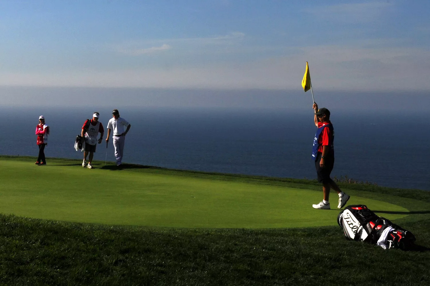 Golfers on the green at Torrey Pines with parachutists in the sky at Genesis Invitational