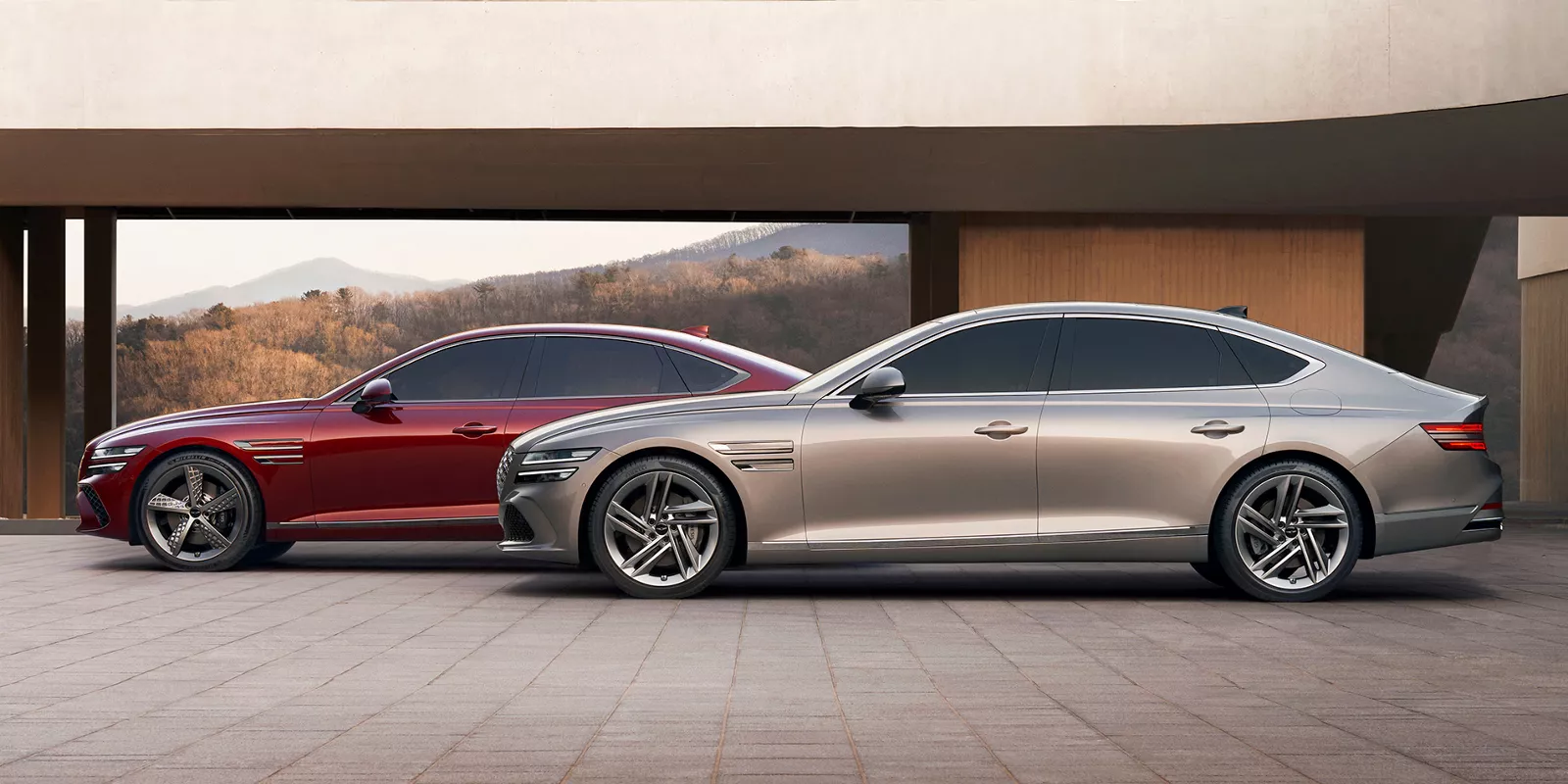 Two Genesis G80s parked in front of a modern building