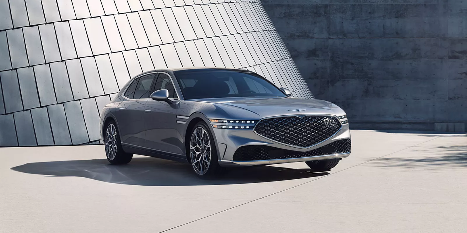 Gray Genesis G90 parked in front of contemporary steel and concrete building