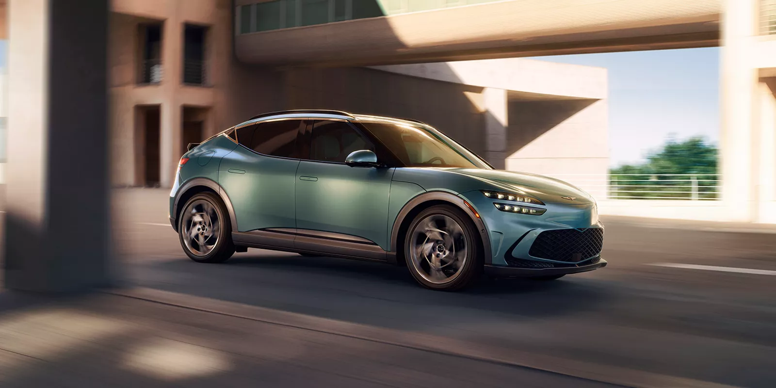 Mint-color Genesis GV60 driving beneath an overpass