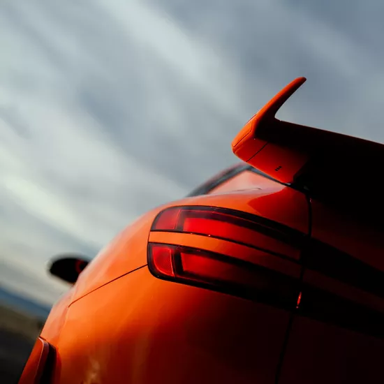 3/4 rear driver side close-up of tail light and spoiler on orange Genesis GV60 Magma