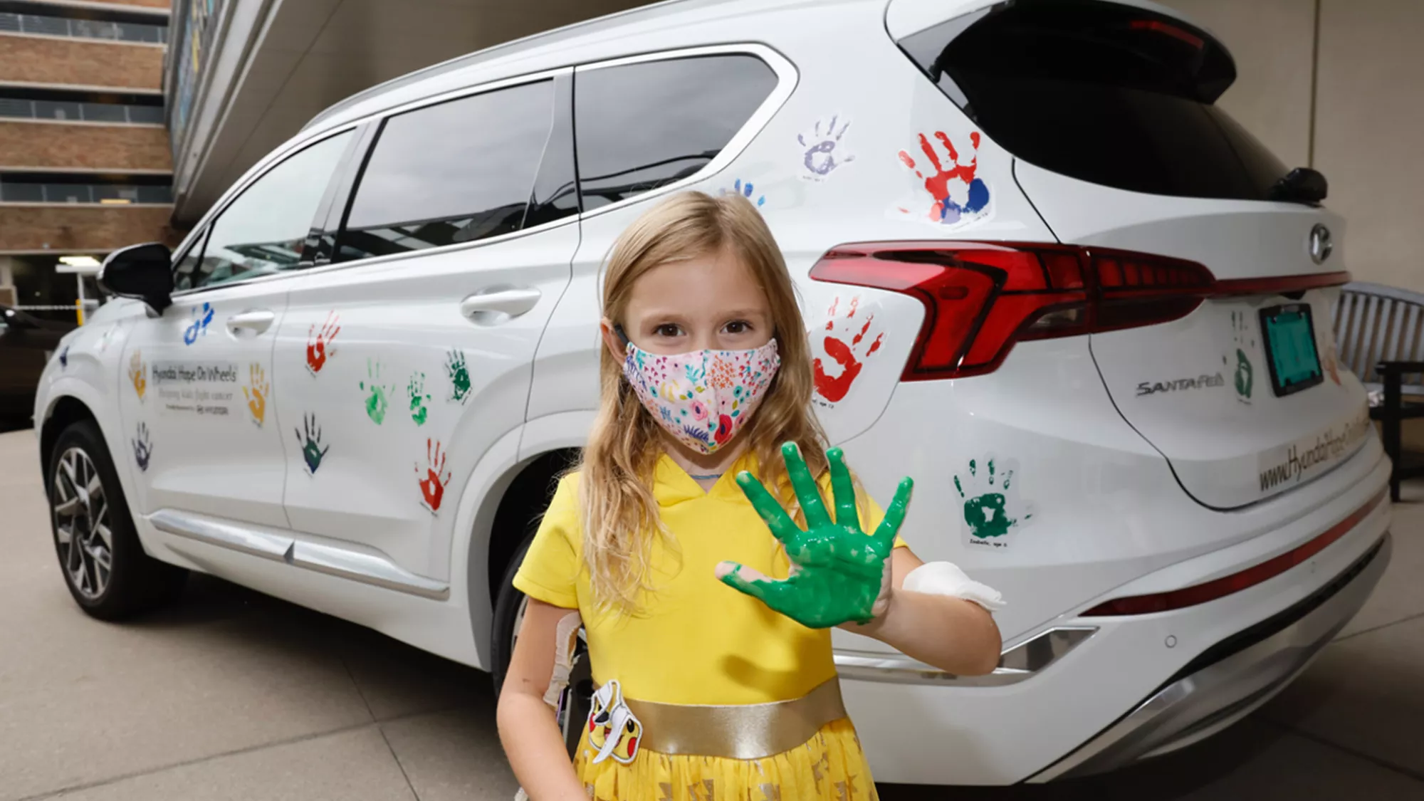 Niña con huella de una mano junto a un vehículo Hyundai