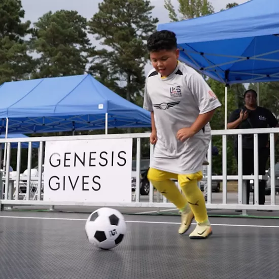 Children playing soccer at a Genesis-sponsored outdoor event