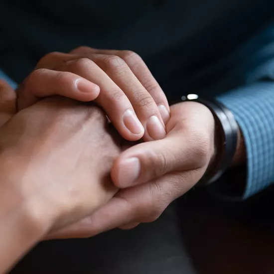 A close-up image of the clasped hands of two people