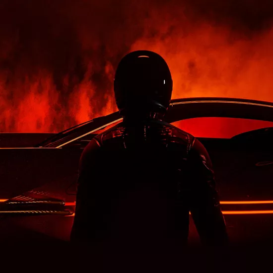 Silhouette of a driver standing in front of a black volcanic lava background