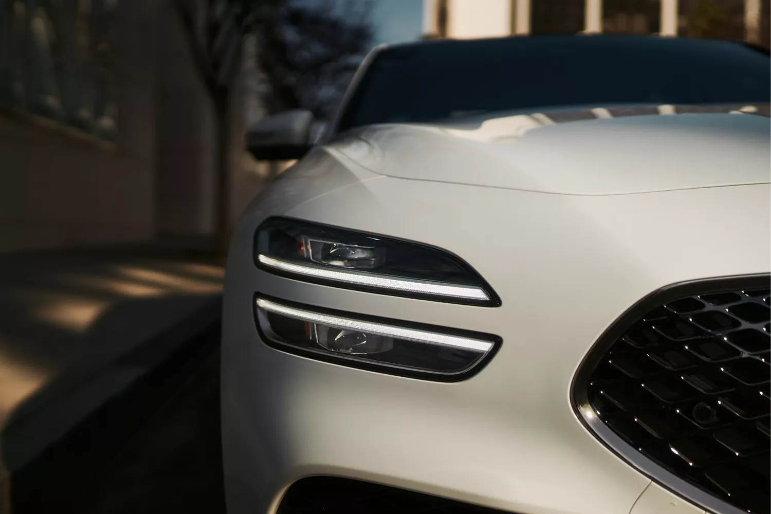 7/8 front passenger side closeup of headlamp and grille on 2027 Genesis G70 in Alta White