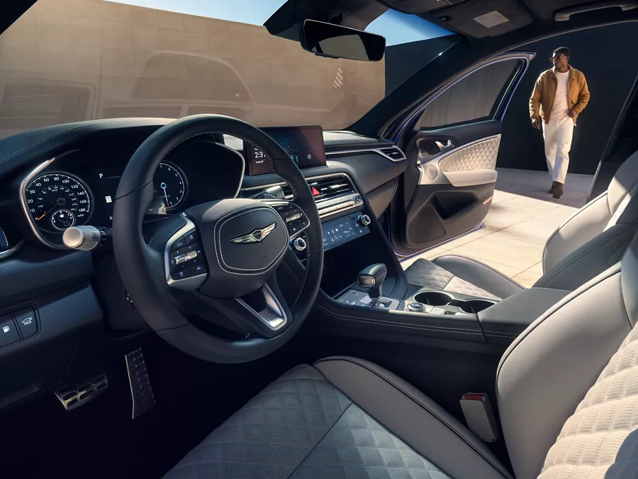 Man walking toward open passenger door, seen from driver seat of Genesis G70 w/ Fog Gray seats