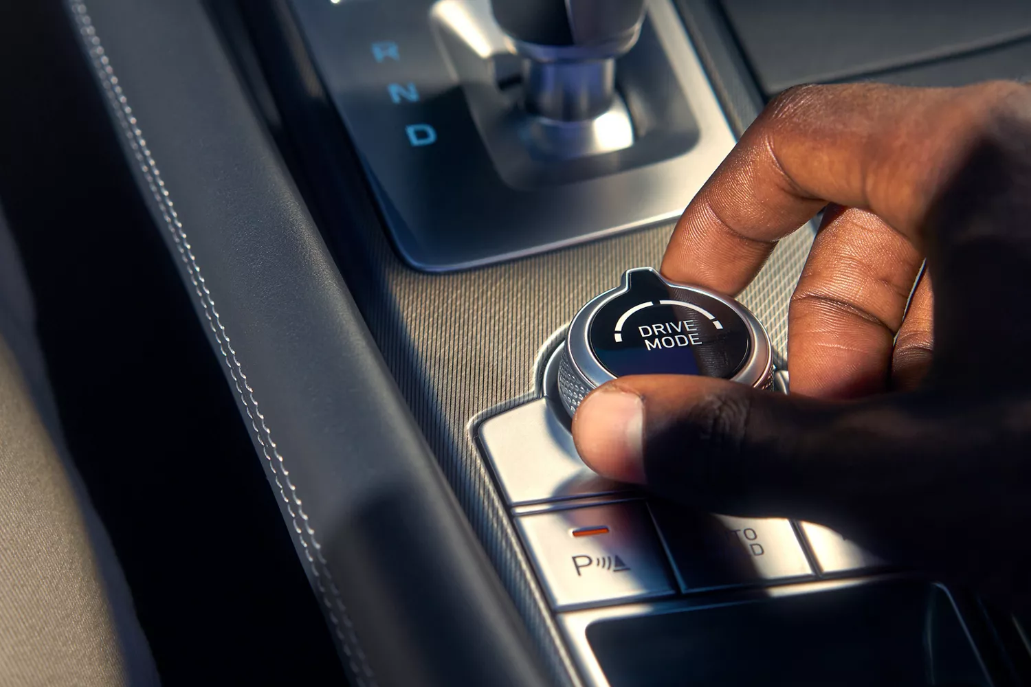 Close up of hand grasping dial that reads "Drive Mode" on center console of Genesis G70