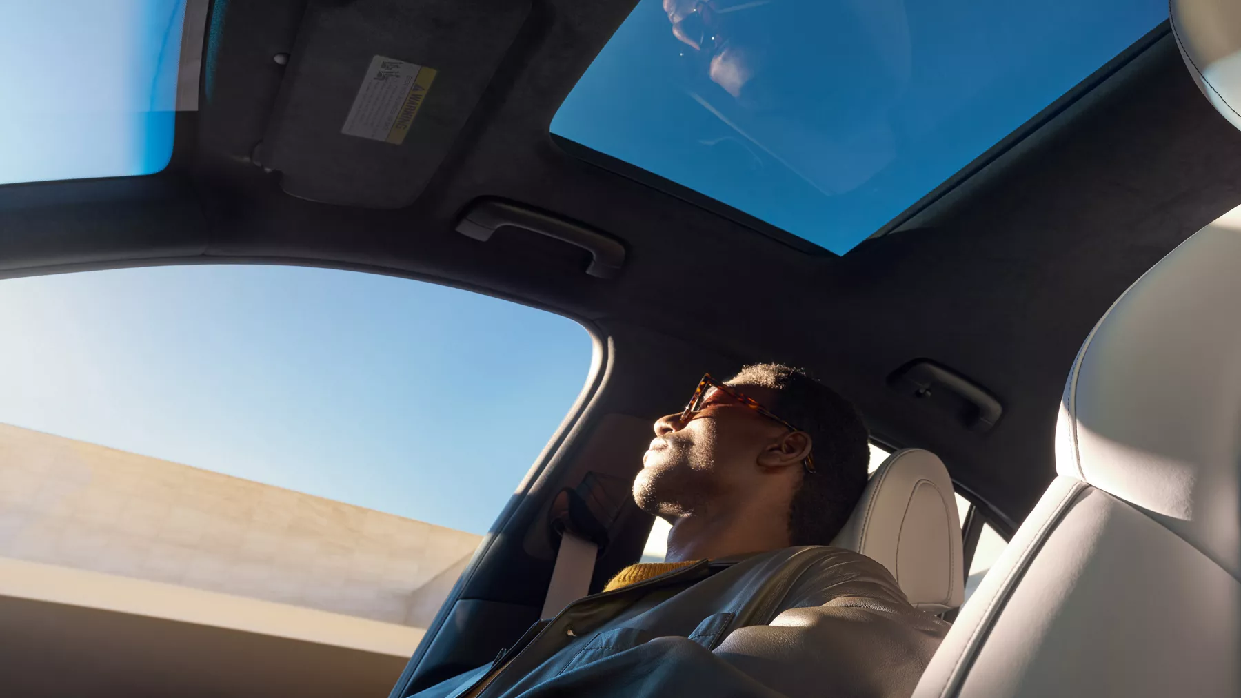 Low angle shot from driver side of man sitting in passenger seat of Genesis G70 3.3T Sport Prestige
