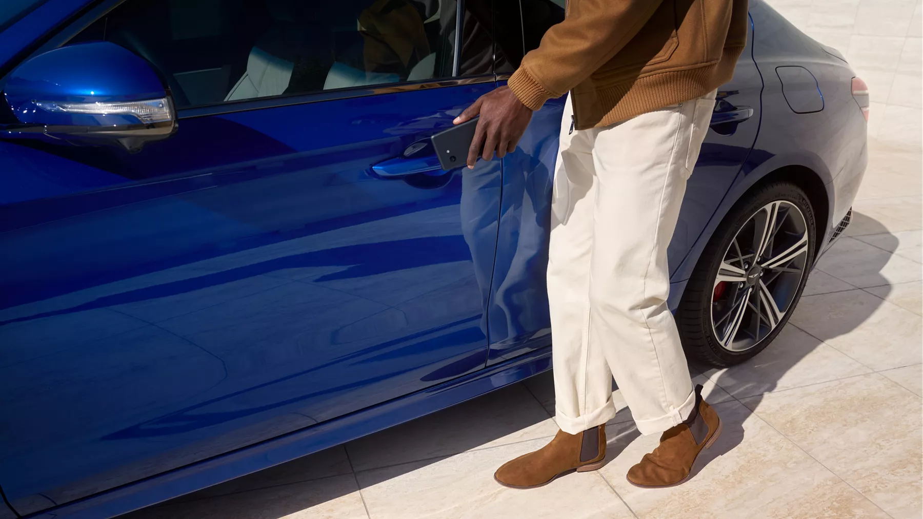 一男子用數位鑰匙解鎖 Genesis G70 (Kawah Blue) 後伸手開啟駕駛側車門的特寫照