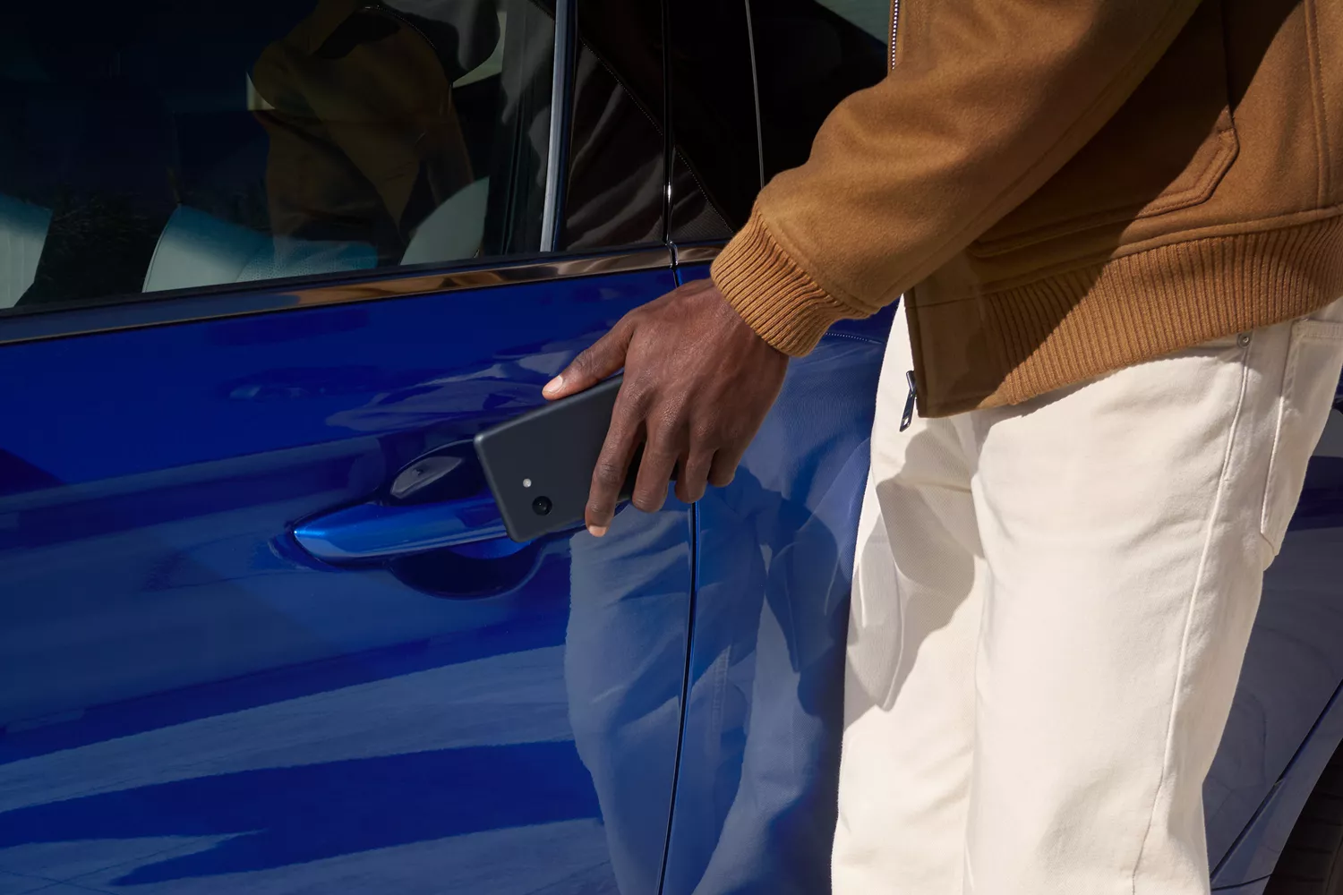 Close up of man reaching to open driver side door with digital key on Genesis G70 in Kawah Blue