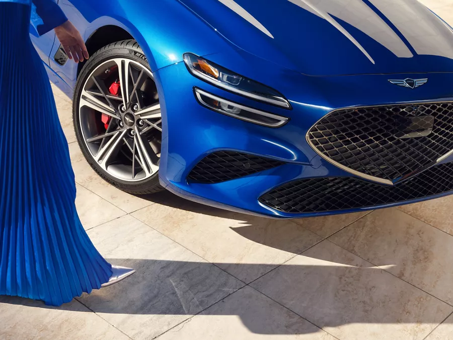 Close up front passenger side view of wheel and grille on Genesis G70 in Kawah Blue
