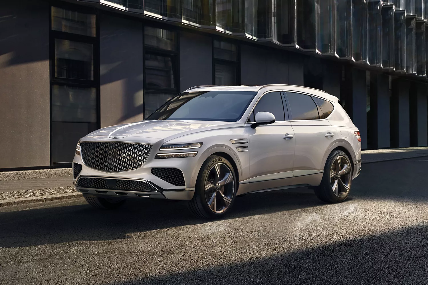 Front 3/4 driver side view of white Genesis GV80 SUV parked on city street