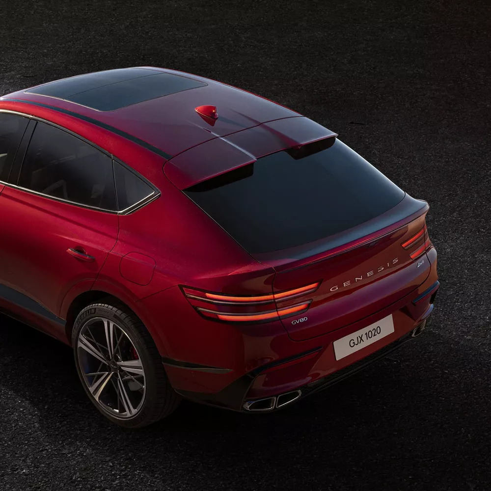 Overhead shot of Genesis GV80 Coupe in Mauna Red parked in a desert landscape at sunset