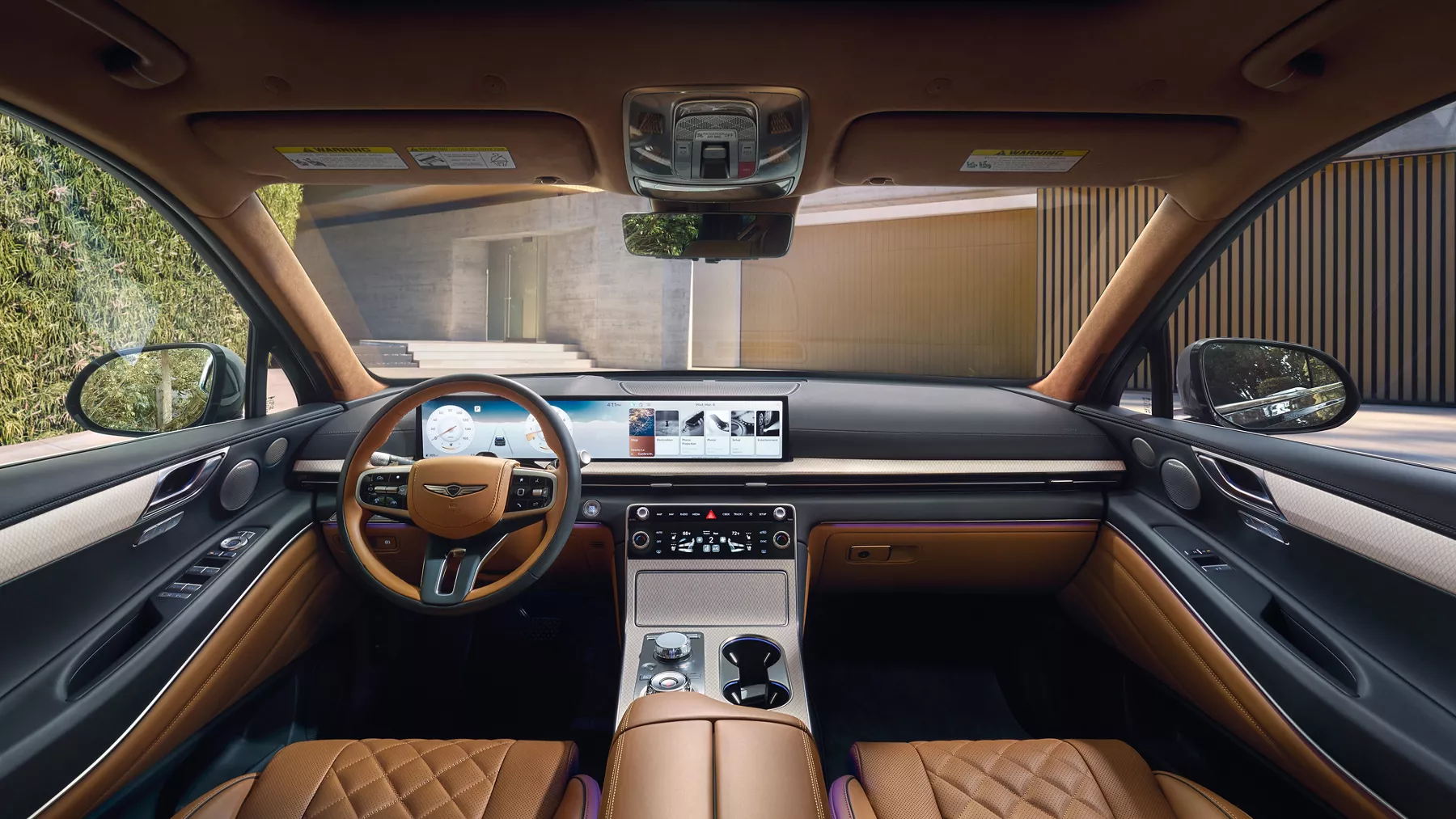 Front dashboard interior shot of Genesis GV80 with tan seats, parked in driveway of modern home