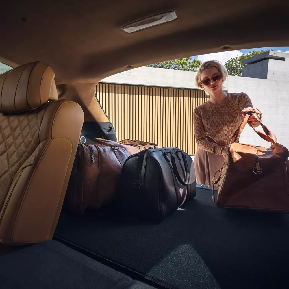Interior view from trunk of woman loading bags into rear cargo of Genesis GV80