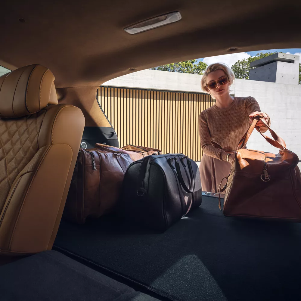 Interior shot from trunk of person loading bags into rear cargo of Genesis GV80