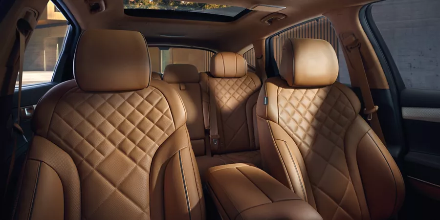 View of Genesis GV80 interior from front to rear, with quilted tan leather seats & panoramic sunroof