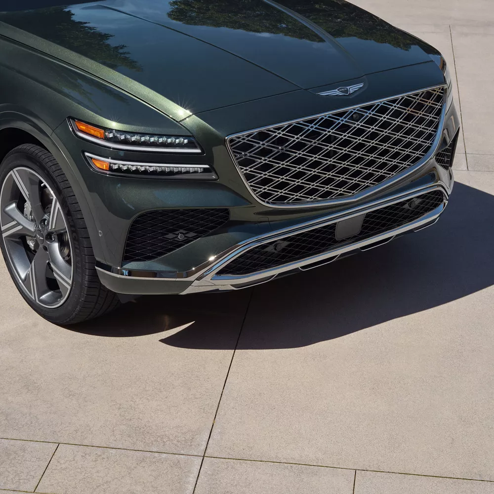 Front close up view of green Genesis GV80 SUV with signature grille and headlights