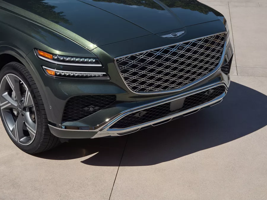 Front close up view of green Genesis GV80 SUV with signature grille and headlights