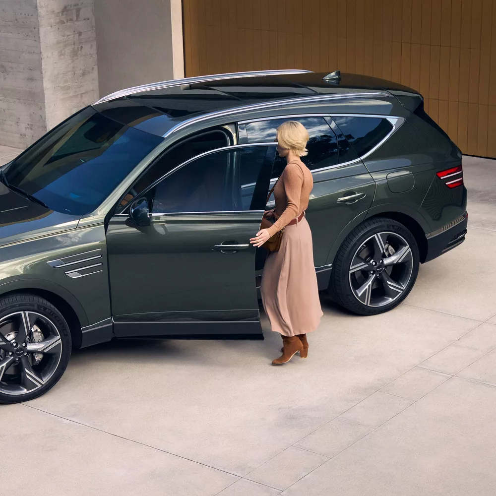 Storr Green Genesis GV80 luxury SUV parked on concrete driveway with driver opening driver side door