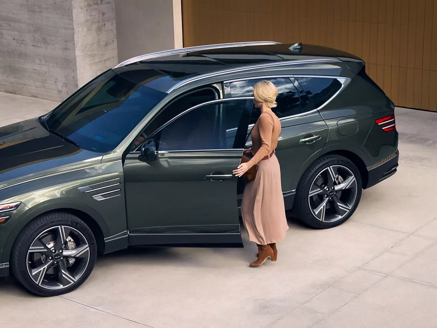 Storr Green Genesis GV80 luxury SUV parked on concrete driveway with driver opening driver side door