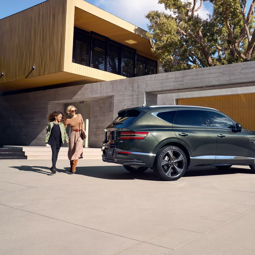 Front passenger side view of Genesis GV80 in Storr Green parked at a home w/ people walking behind