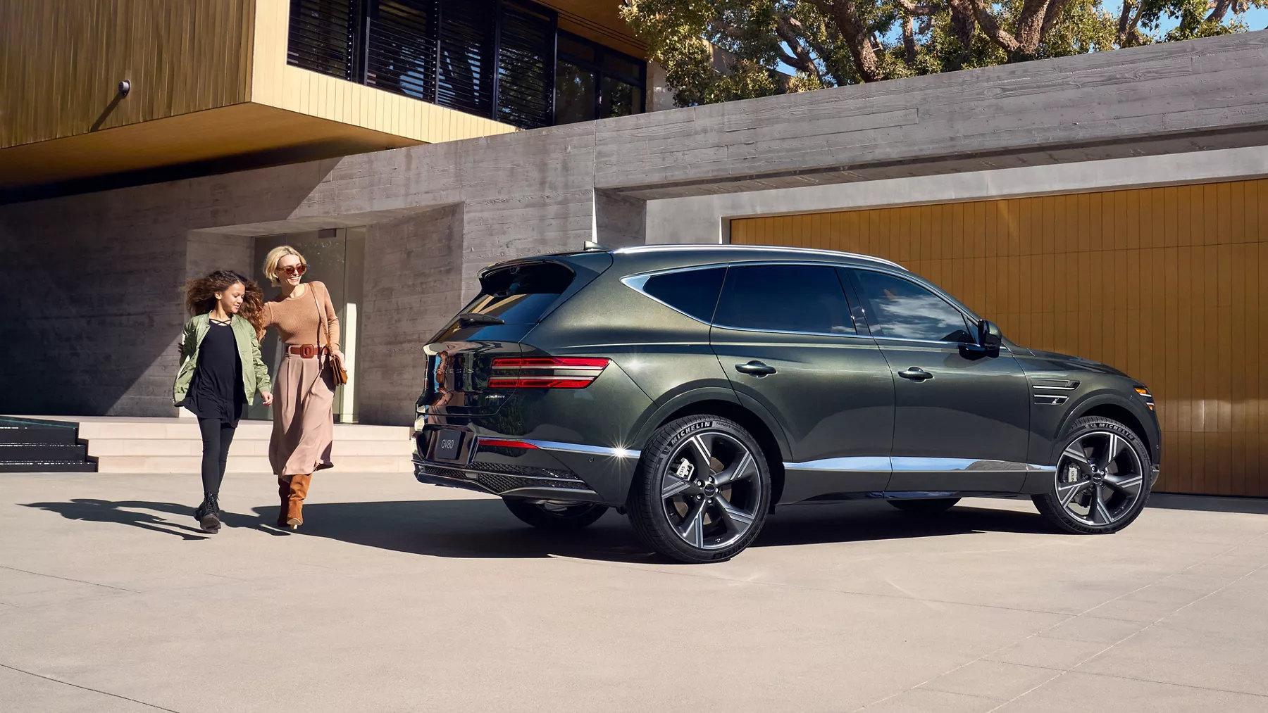 Front passenger side view of Genesis GV80 in Storr Green parked at a home w/ people walking behind