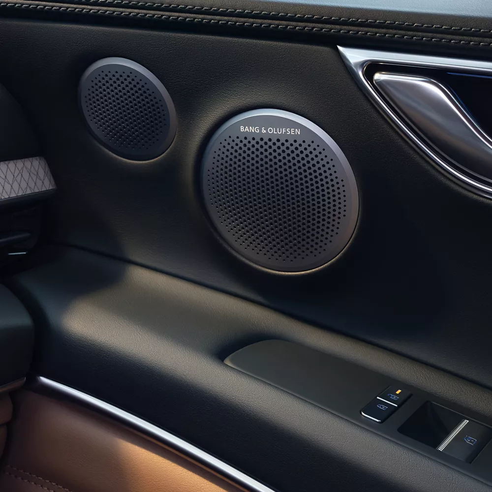 Interior closeup of passenger door panel featuring Bang & Olufsen sound system inside Genesis GV80