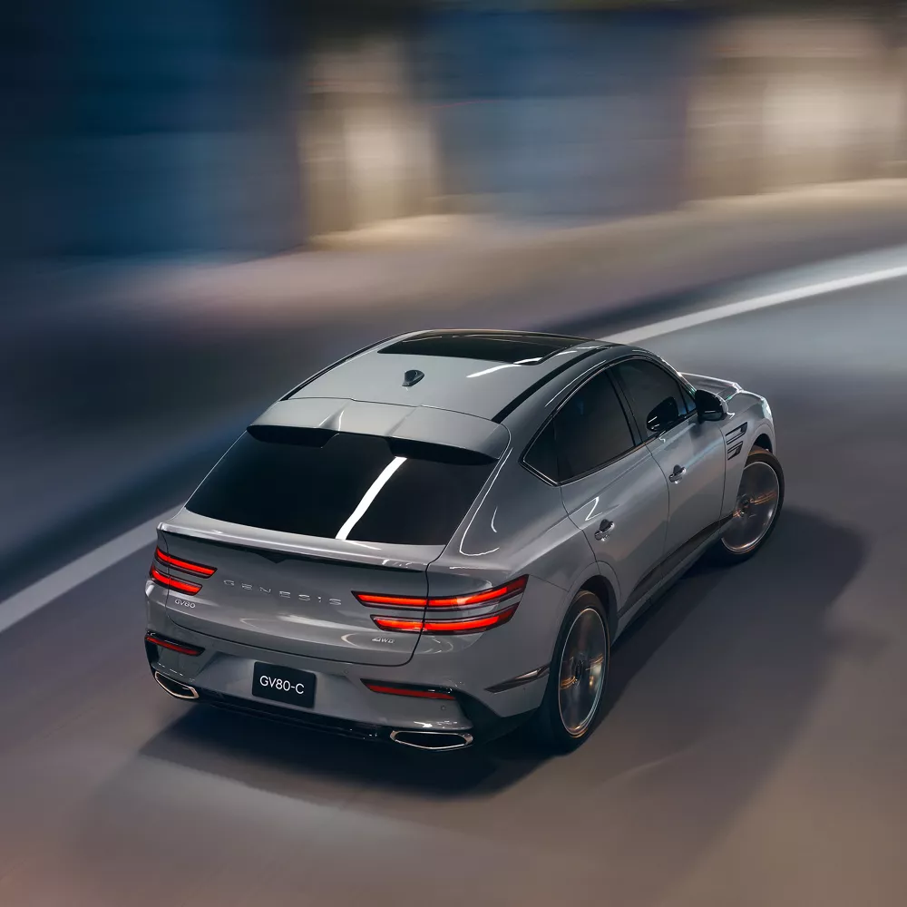 Rear overhead view of Genesis GV80 Coupe in Bering Blue driving through a parking structure