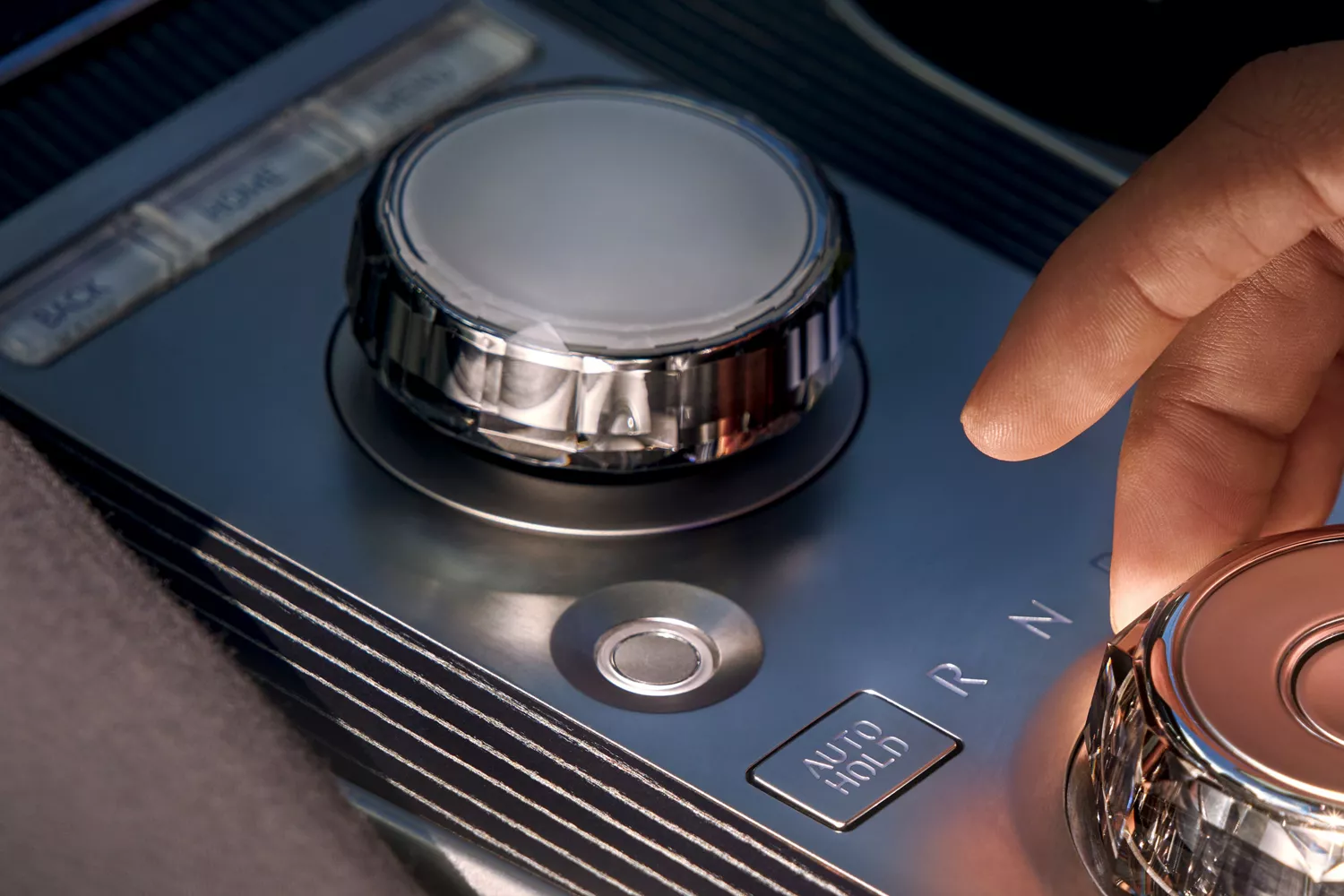 Interior closeup of hand using shift-by-wire knob on center console inside Genesis GV80 Coupe