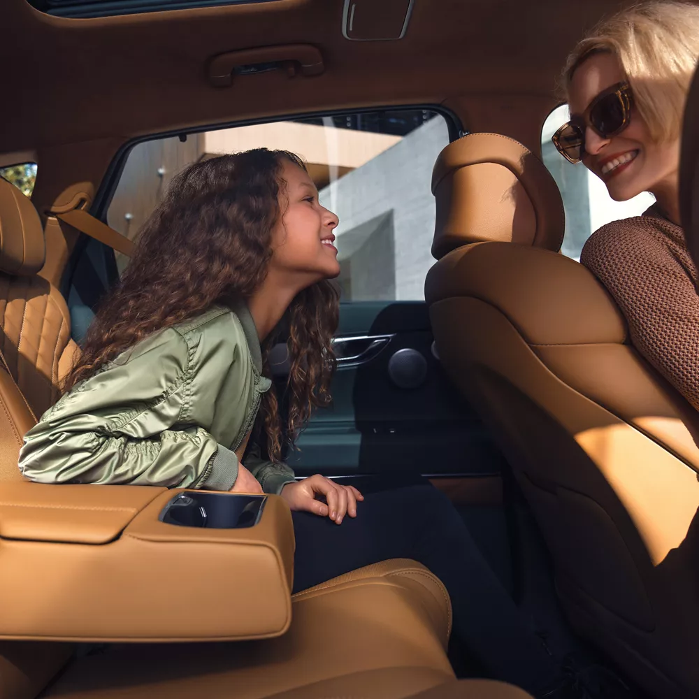 Interior close up front and rear passengers engaging, inside Genesis GV80 with tan leather seats