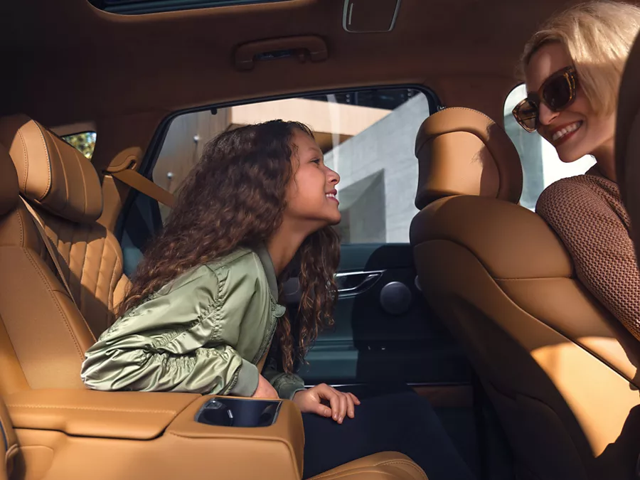 Interior close up front and rear passengers engaging, inside Genesis GV80 with tan leather seats