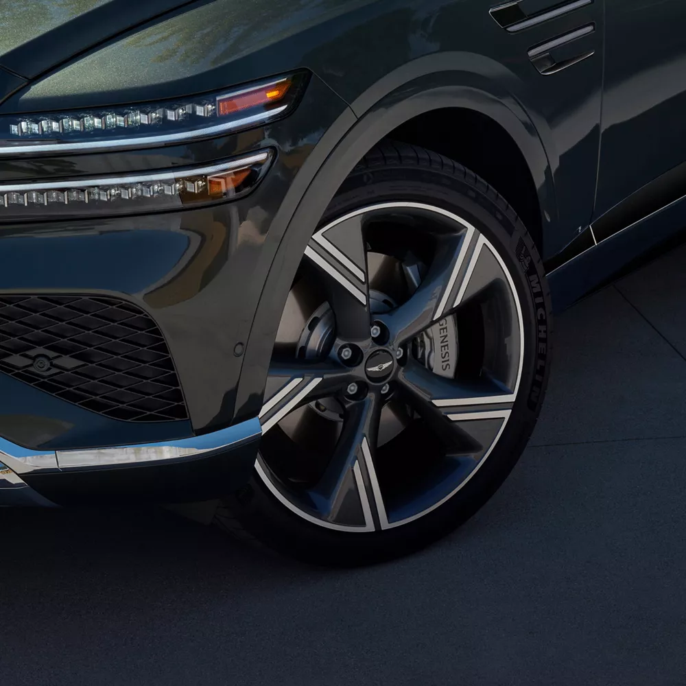 Close-up of Genesis GV80 in Storr Green showing front wheel and LED headlight design details