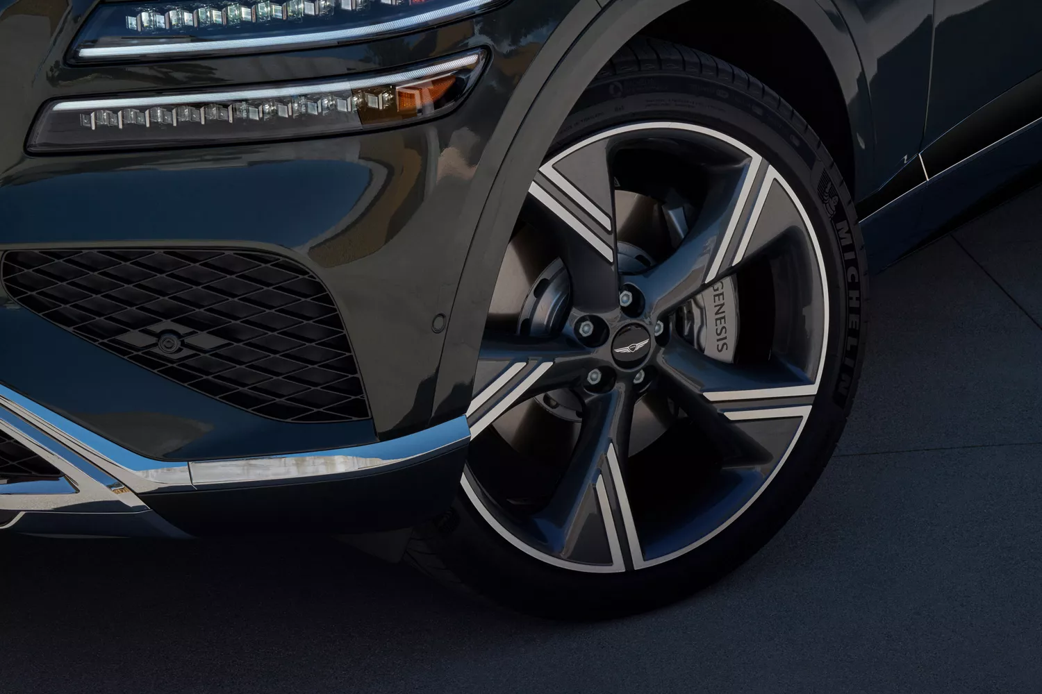 Exterior front driver side closeup of wheel and headlight details on Genesis GV80 in Storr Green