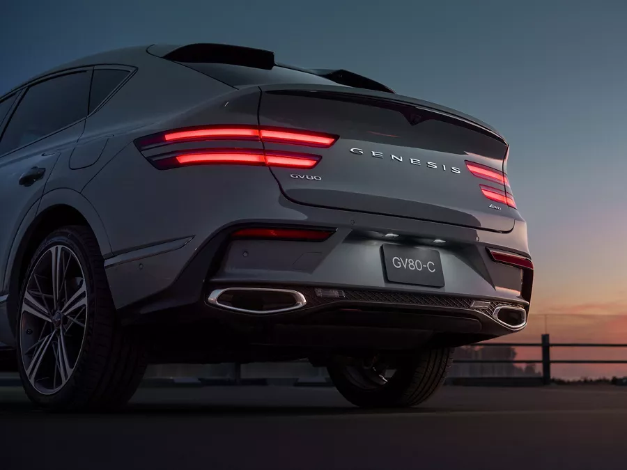 Rear view of Genesis GV80 Coupe in Bering Blue at sunset with illuminated taillights