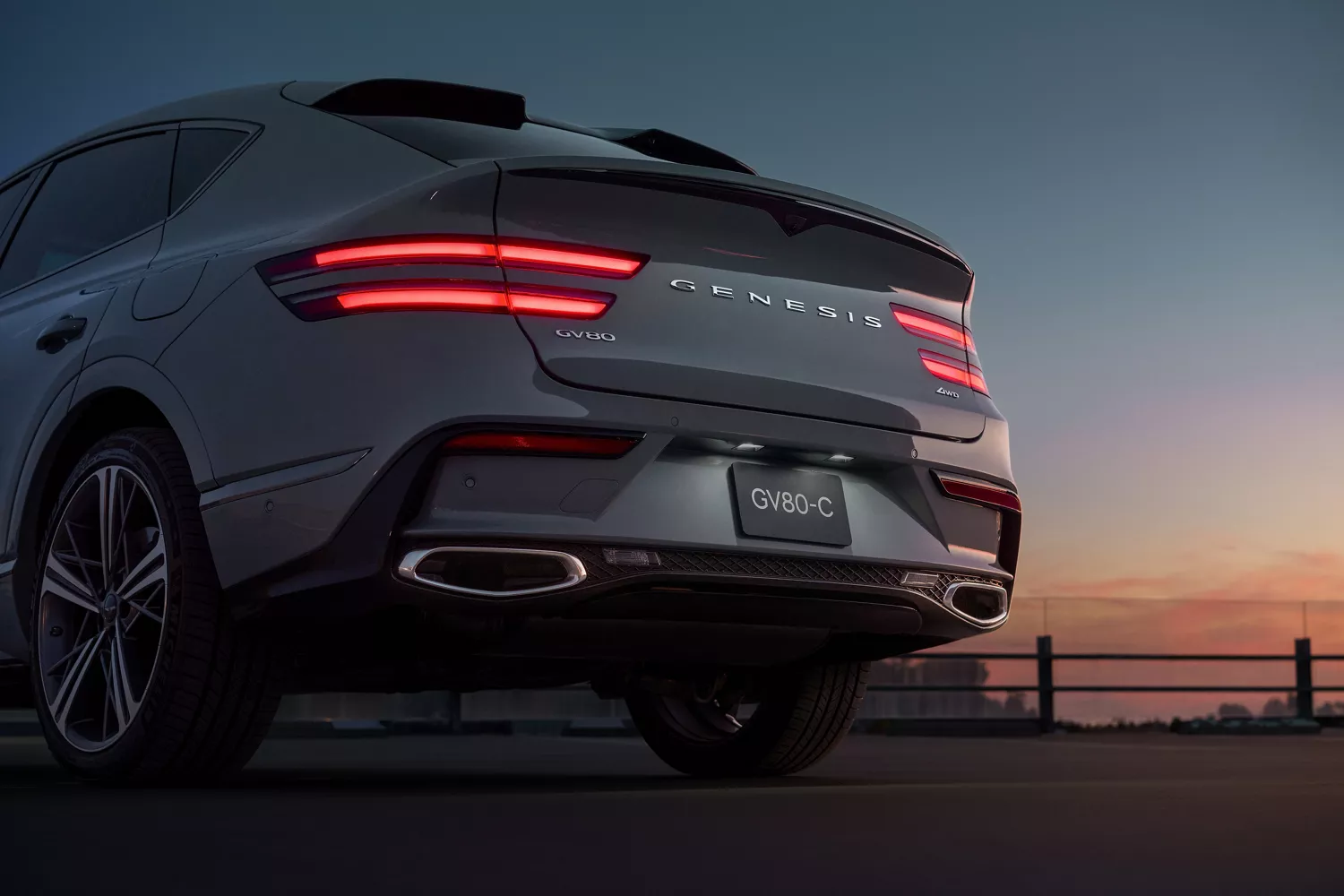 Rear view of Genesis GV80 Coupe in Bering Blue at sunset with illuminated taillights