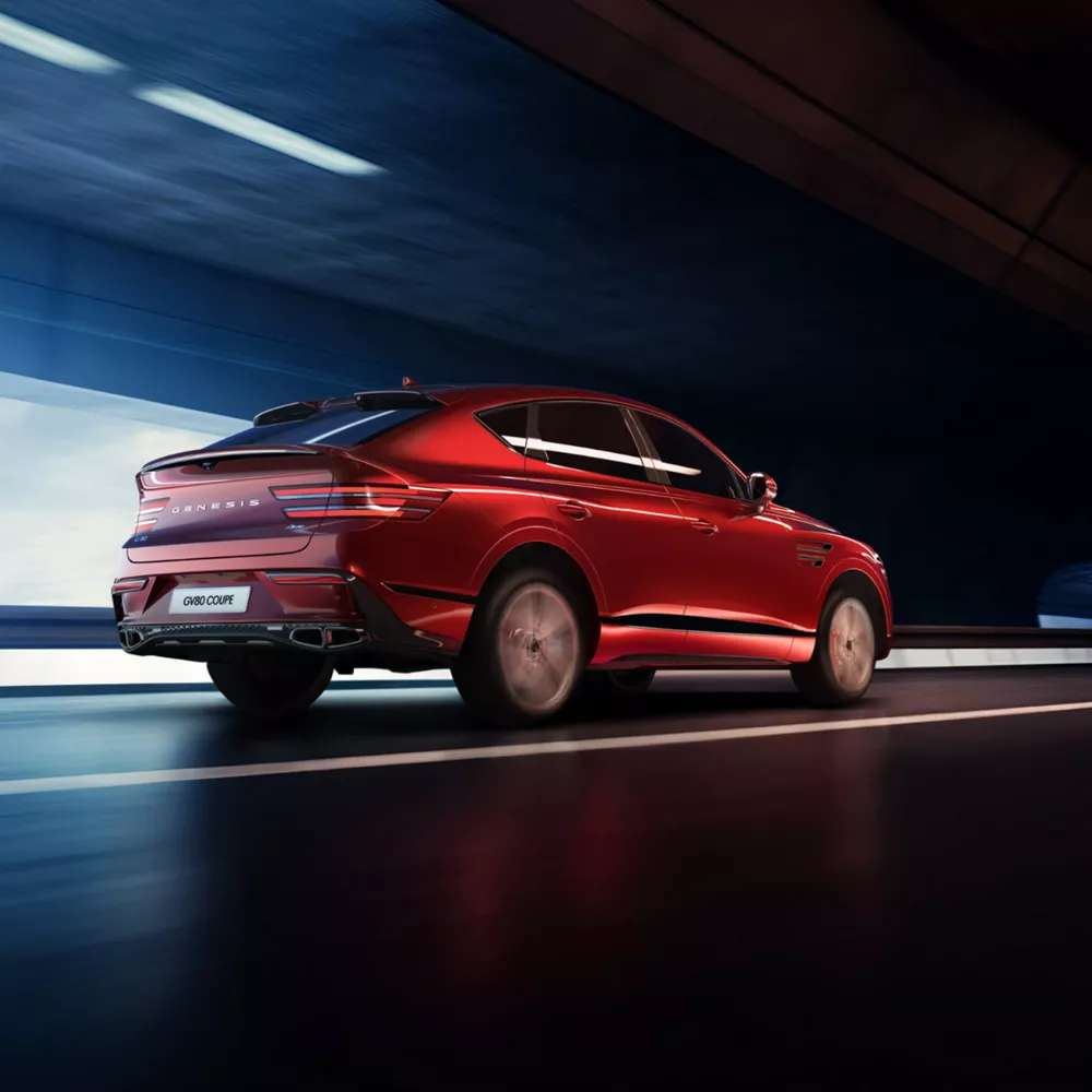 7/8 rear passenger side angle of Genesis GV80 Coupe in Mauna Red driving through a tunnel