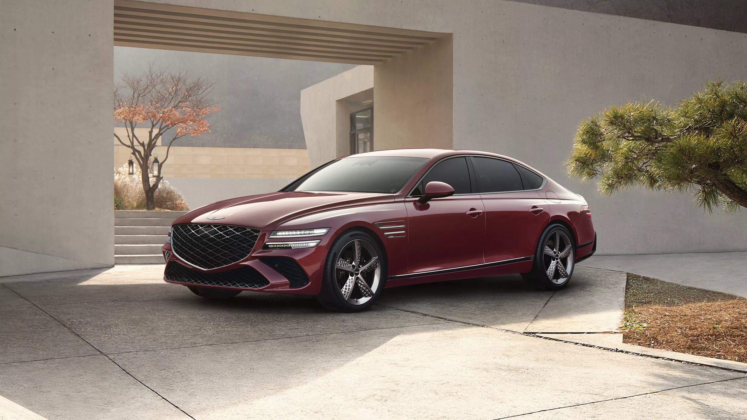 7/8 front driver side angle of Genesis G80 in Cavendish Red parked in driveway of modern house