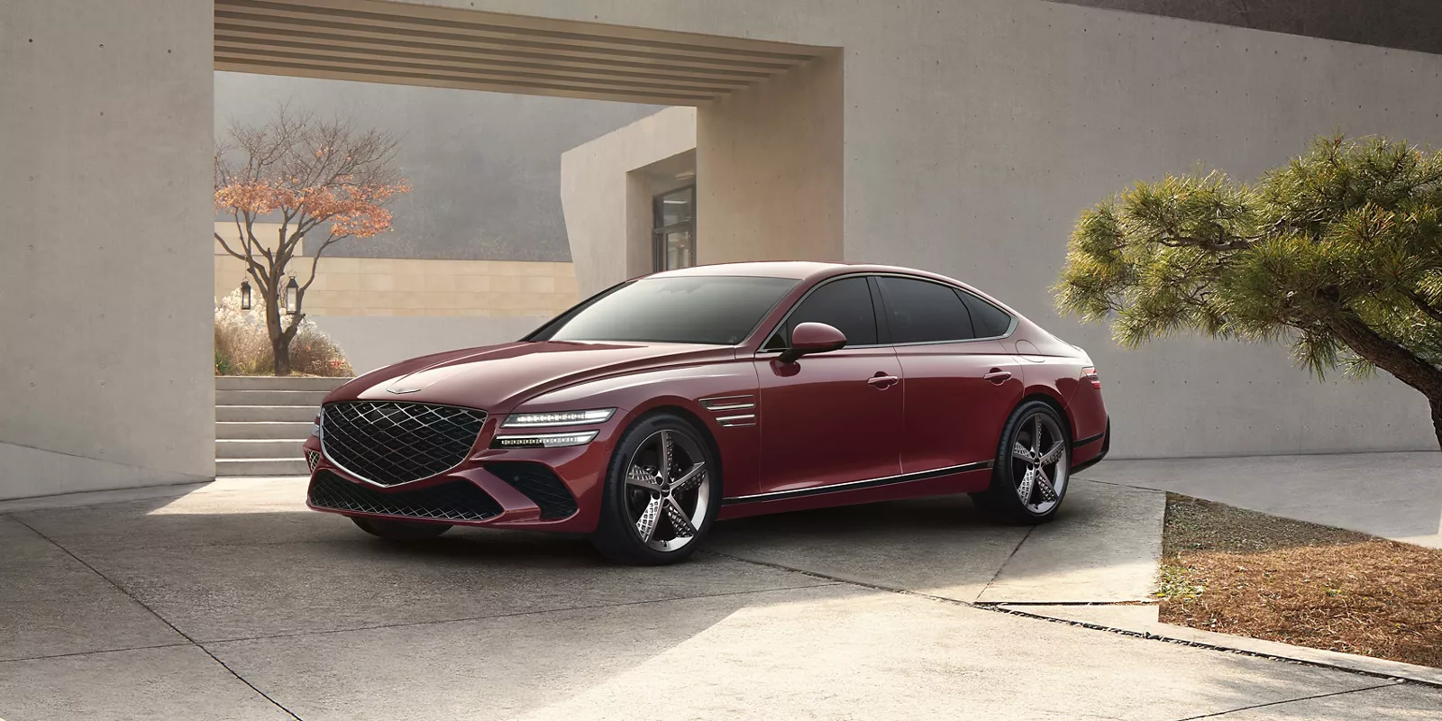 7/8 front driver side angle of Genesis G80 in Cavendish Red parked in driveway of modern house