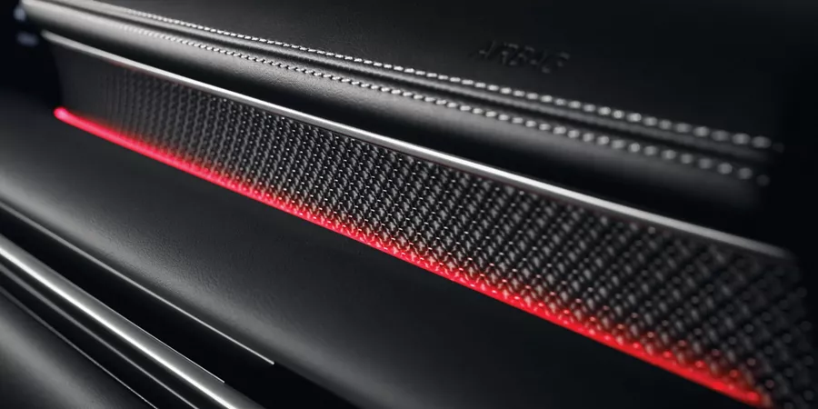 Interior closeup of carbon fiber accent with red ambient lighting inside Genesis G80