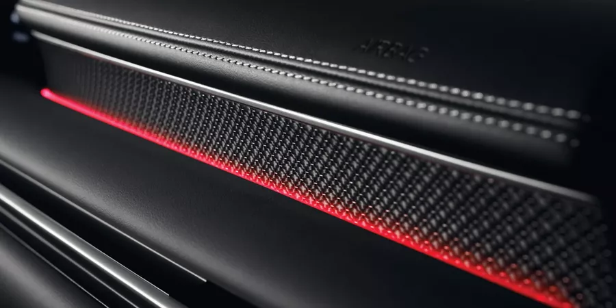Interior close up of black carbon fiber accent with red ambient light in Genesis G80