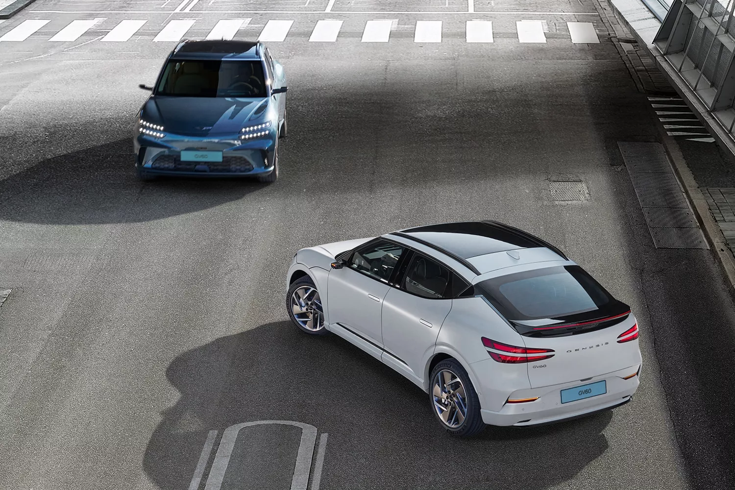 Two perpendicular Genesis GV60s at city intersection highlighting forward collision avoidance feature