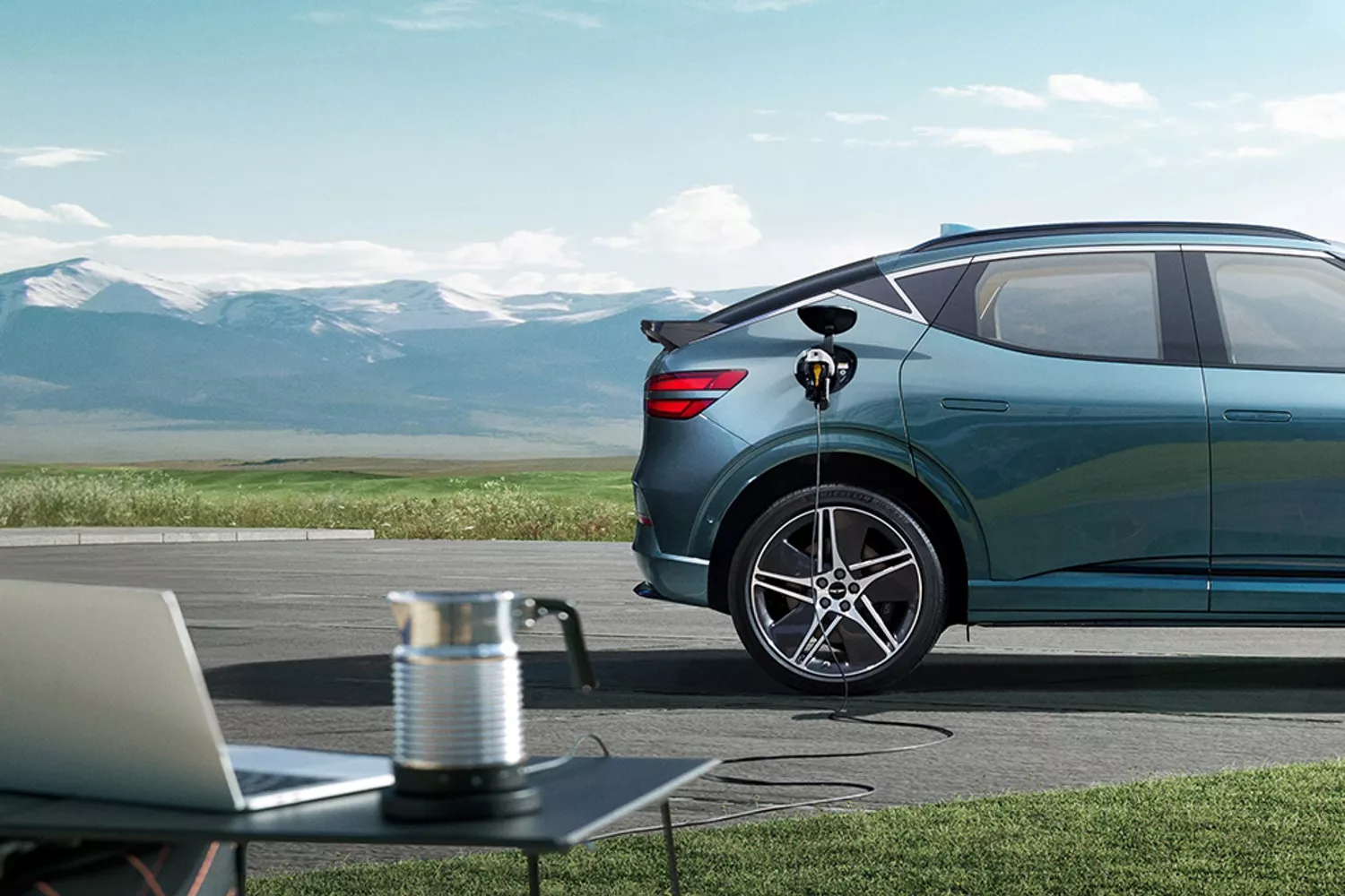 2026 Genesis GV60 in Tromso Green charging with mountain backdrop and clear sky scenery