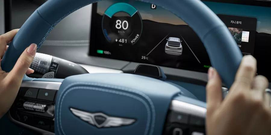 Interior close up of 2026 Genesis GV60 digital dashboard through steering wheel