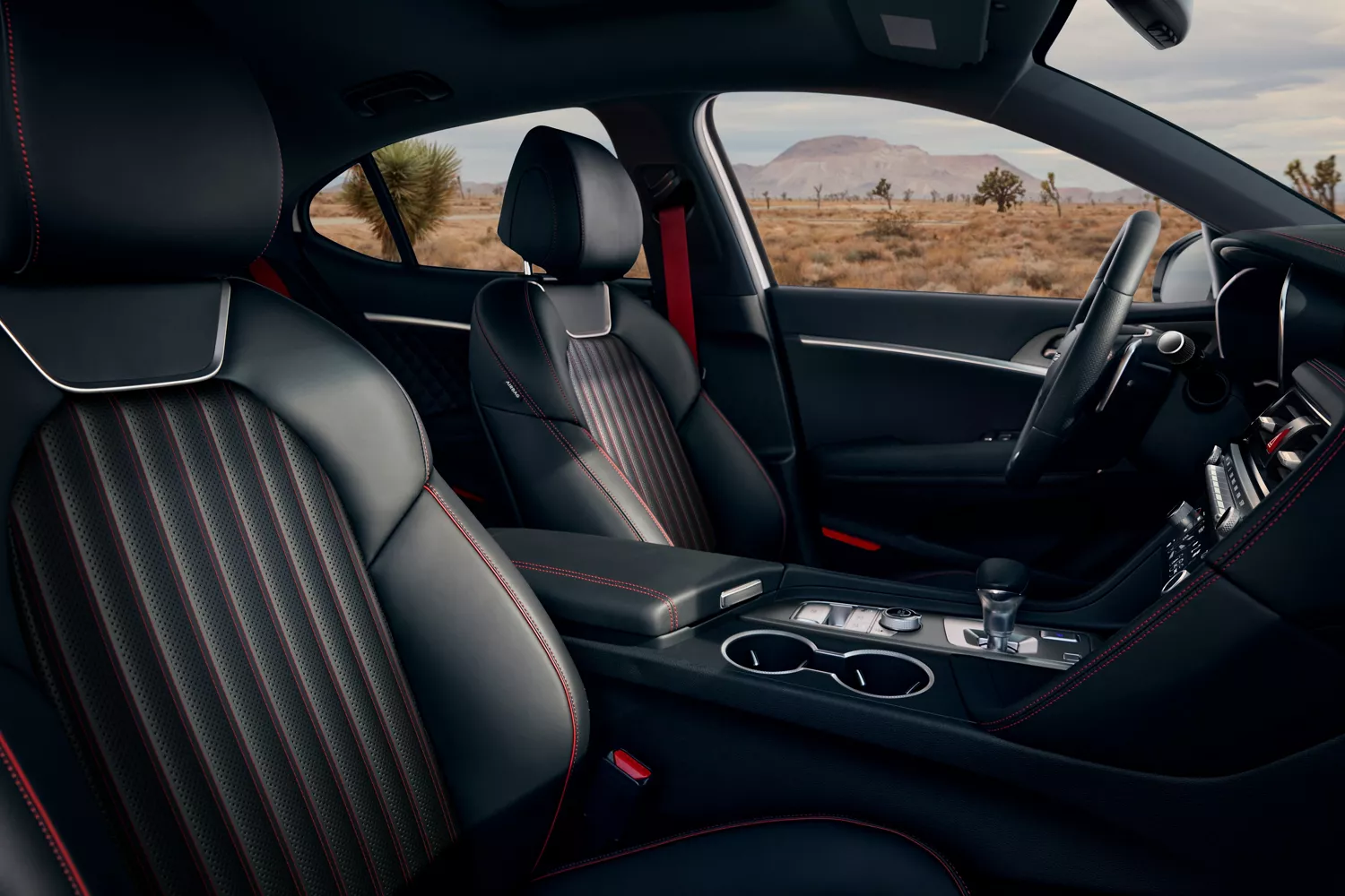 Interior passenger door POV of front seats in black with red stitching, inside 2027 Genesis G70