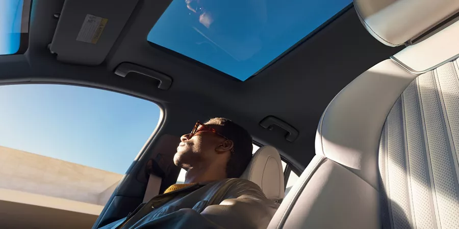 Low angle shot from driver side of man sitting in passenger seat of Genesis G70 3.3T Sport Prestige
